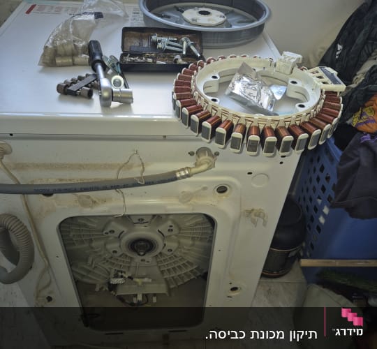 מכונת כביסה פתוחה עם חלקים וכלים לתיקון